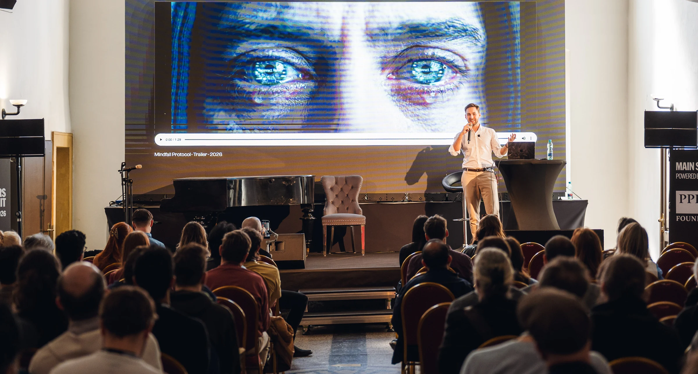 Gedeon Drapák na pódiu Composer Summit Prague, za ním trailer filmu Mindfall Protocol na plátně a zaplněný sál